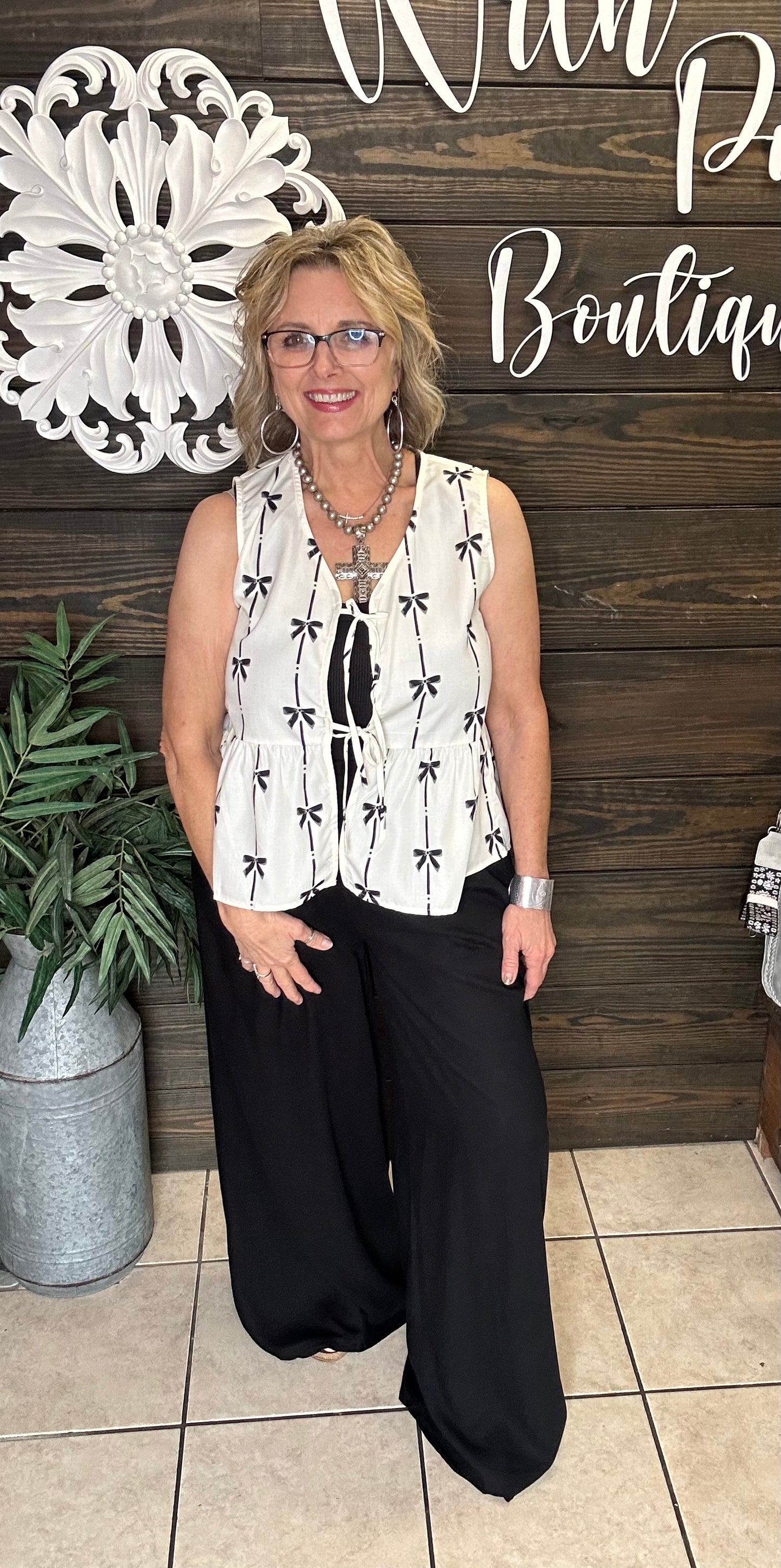 100% polyester cream colored vest with printed black bows, 2 ties in front to add to look, sleeveless. 