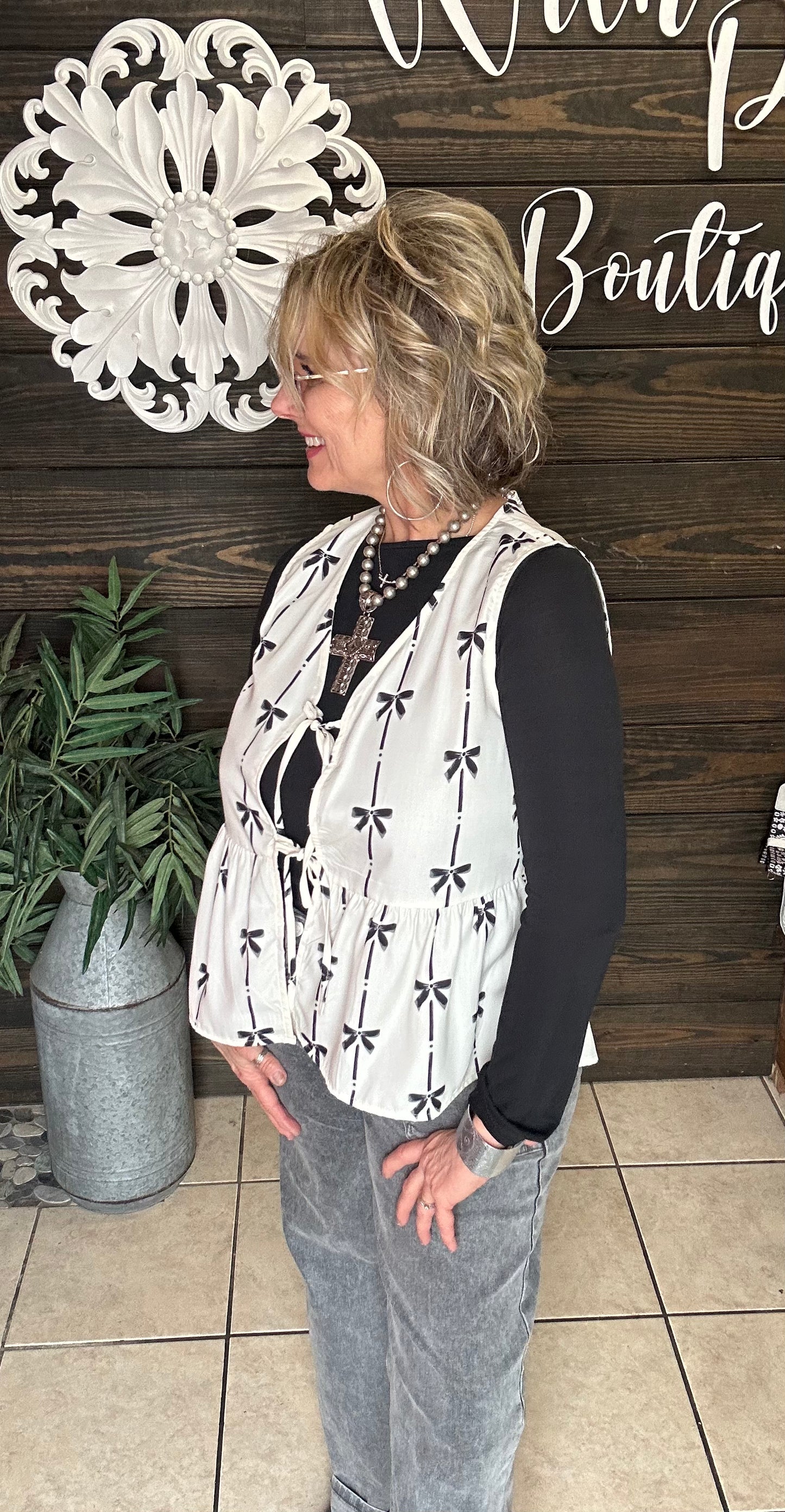 100% polyester cream colored vest with printed black bows, 2 ties in front to add to look, sleeveless. 