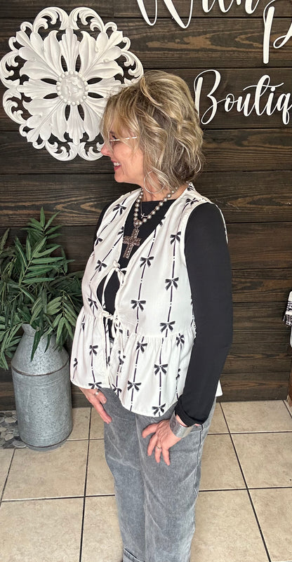 100% polyester cream colored vest with printed black bows, 2 ties in front to add to look, sleeveless. 