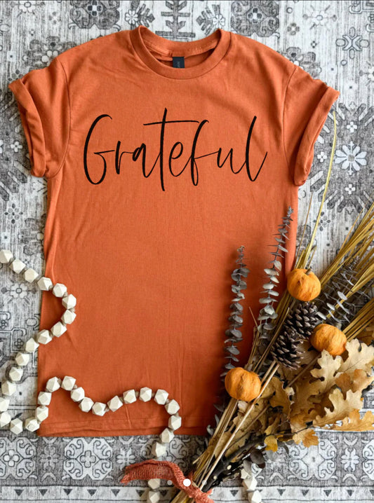 Short sleeve, Gilden brand soft T-shirt in a soft pumpkin color with the graphics, grateful in black across the front.