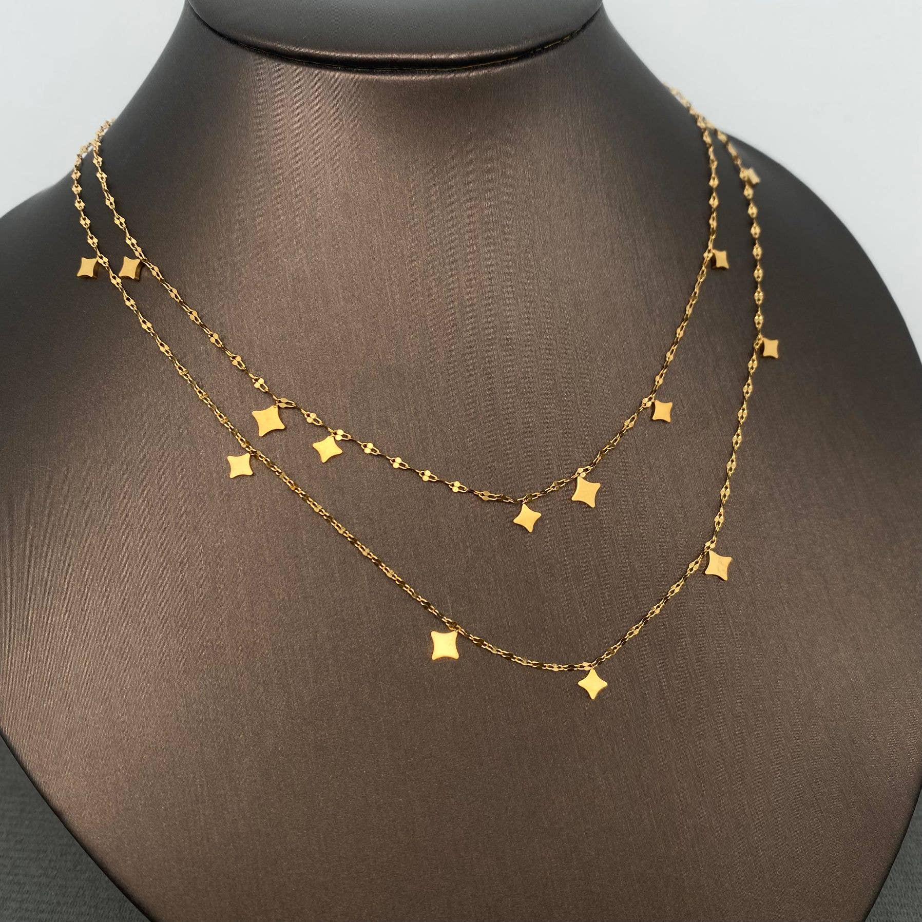 Gold necklace with star-shaped pendants on a mannequin