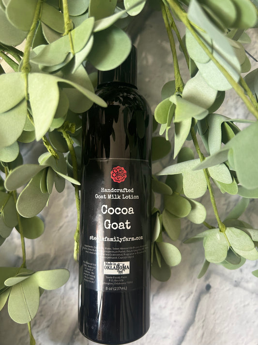 Black bottle of Cocoa goat milk lotion with red label on green leaves