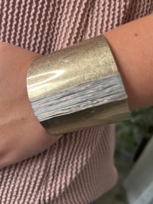 wide gold cuff bracelet with silver wire on arm