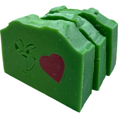 Green Grinch face soap with a red heart and leaf design on a white background