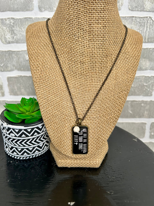 long chain necklace with glass rectangle pendant with "The Only One qualified to throw stones didn't" message, adorned with a small white bead.