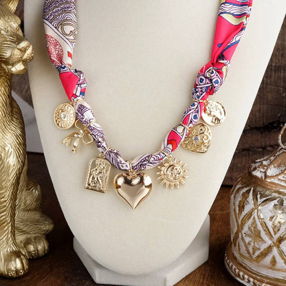 Necklace with gold charms and colorful fabric on a mannequin bust.