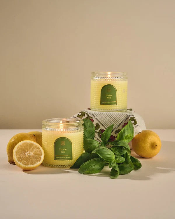 Two lemon-scented candles with lemons and mint leaves on a neutral background