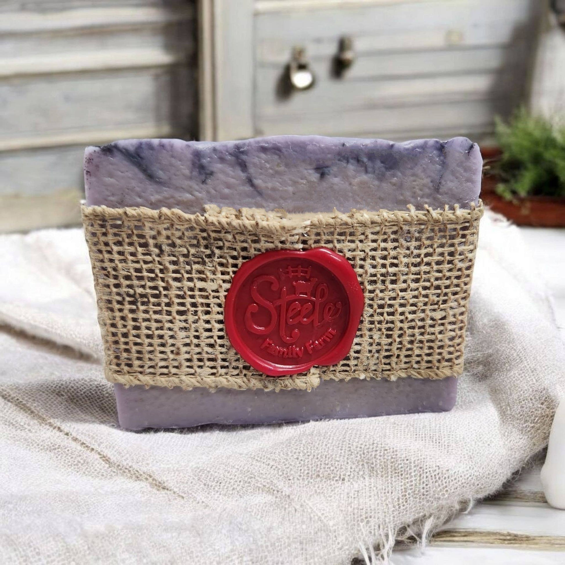 Bar of soap in a burlap container with a red logo on a textured surface