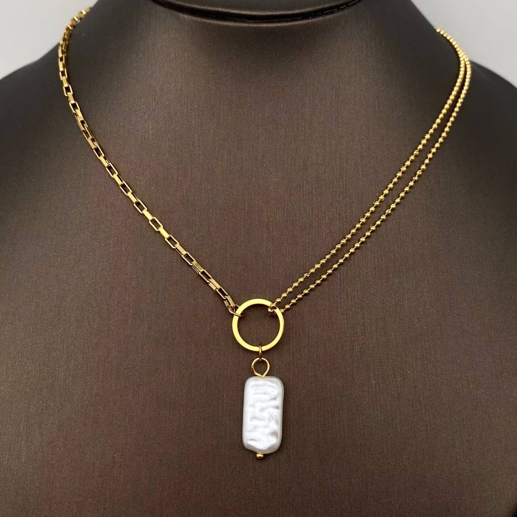 Gold necklace with a white pearl pendant on a mannequin