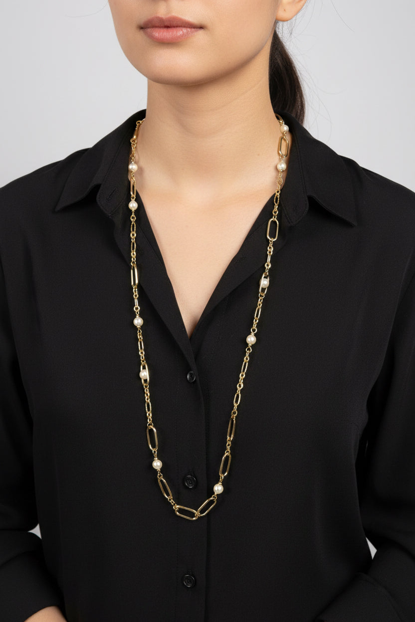 a lady wearing a black shirt and a gold and pearl long necklace