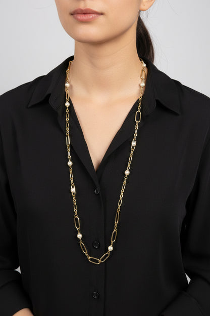a lady wearing a black shirt and a gold and pearl long necklace