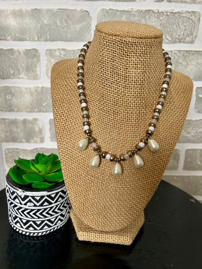 . This unique piece features layered beads of different shapes, adorned with 5 teardrop pearly stones. Combining beauty and classic style, this necklace is sure to make a statement. Elevate any outfit with this must-have accessory.

approx. 7.5' hanging length plus 2.5" extender