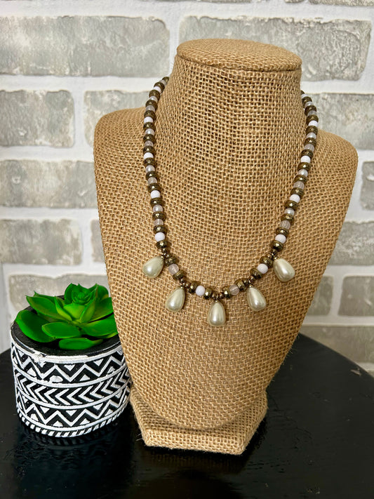 . This unique piece features layered beads of different shapes, adorned with 5 teardrop pearly stones. Combining beauty and classic style, this necklace is sure to make a statement. Elevate any outfit with this must-have accessory.

approx. 7.5' hanging length plus 2.5" extender