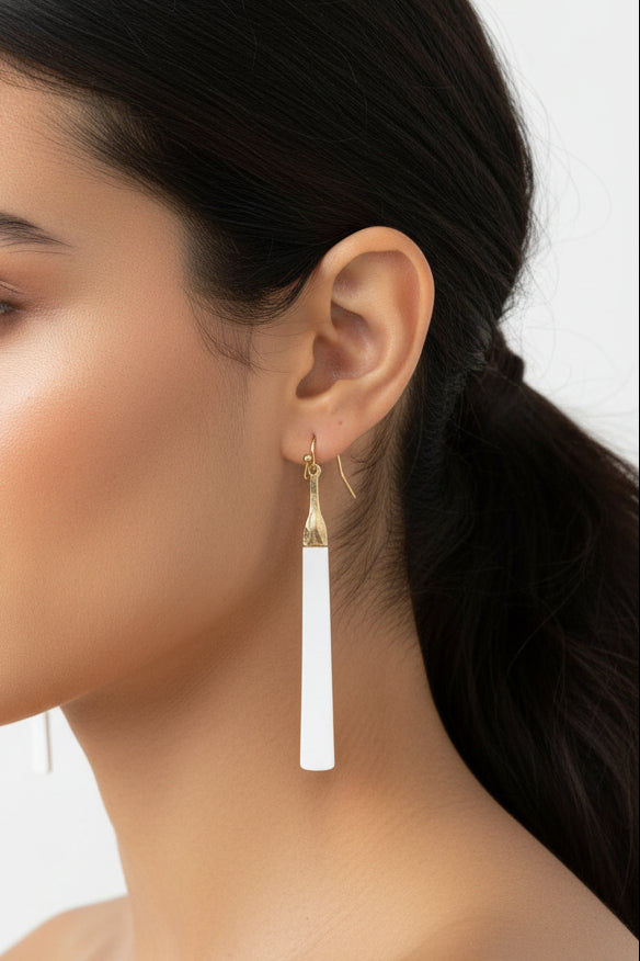 A woman wearing a long bar shaped earring with gold accents