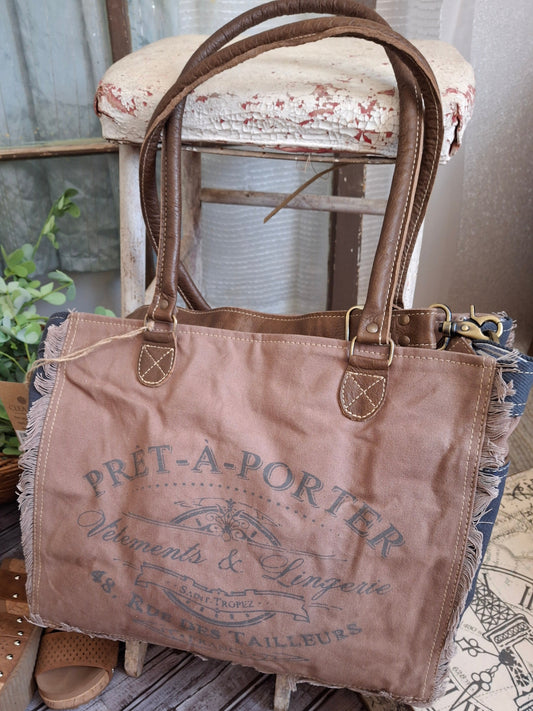 Start your next trip with this vintage inspired Pret-A-Porter Duffle Bag. The retro Parisian embossed print paired with fringe detail makes this bag stand out from the rest! It has ample storage and is a seamless addition to any accessory or travel collection.&nbsp;It features a vintage blue and white stripe lining, three inside pocket, one outside pocket, a large side pocket and an adjustable shoulder strap.&nbsp;