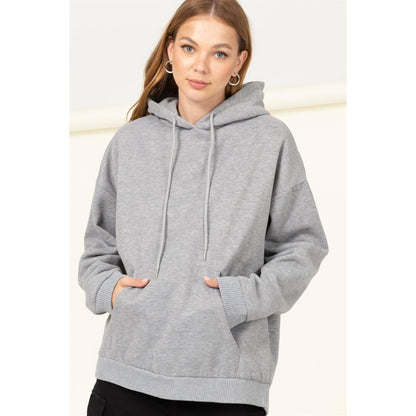 Woman wearing a gray hoodie against a plain background