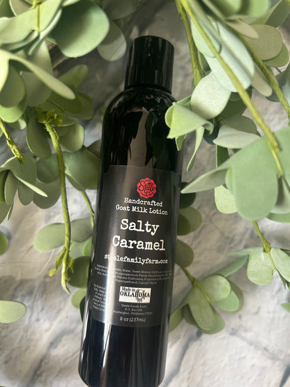 Bottle of Salty Caramel Goat Milk Lotion with green leaves in the background