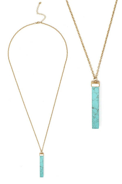 Necklace with turquoise bar pendants on gold chains against a white background