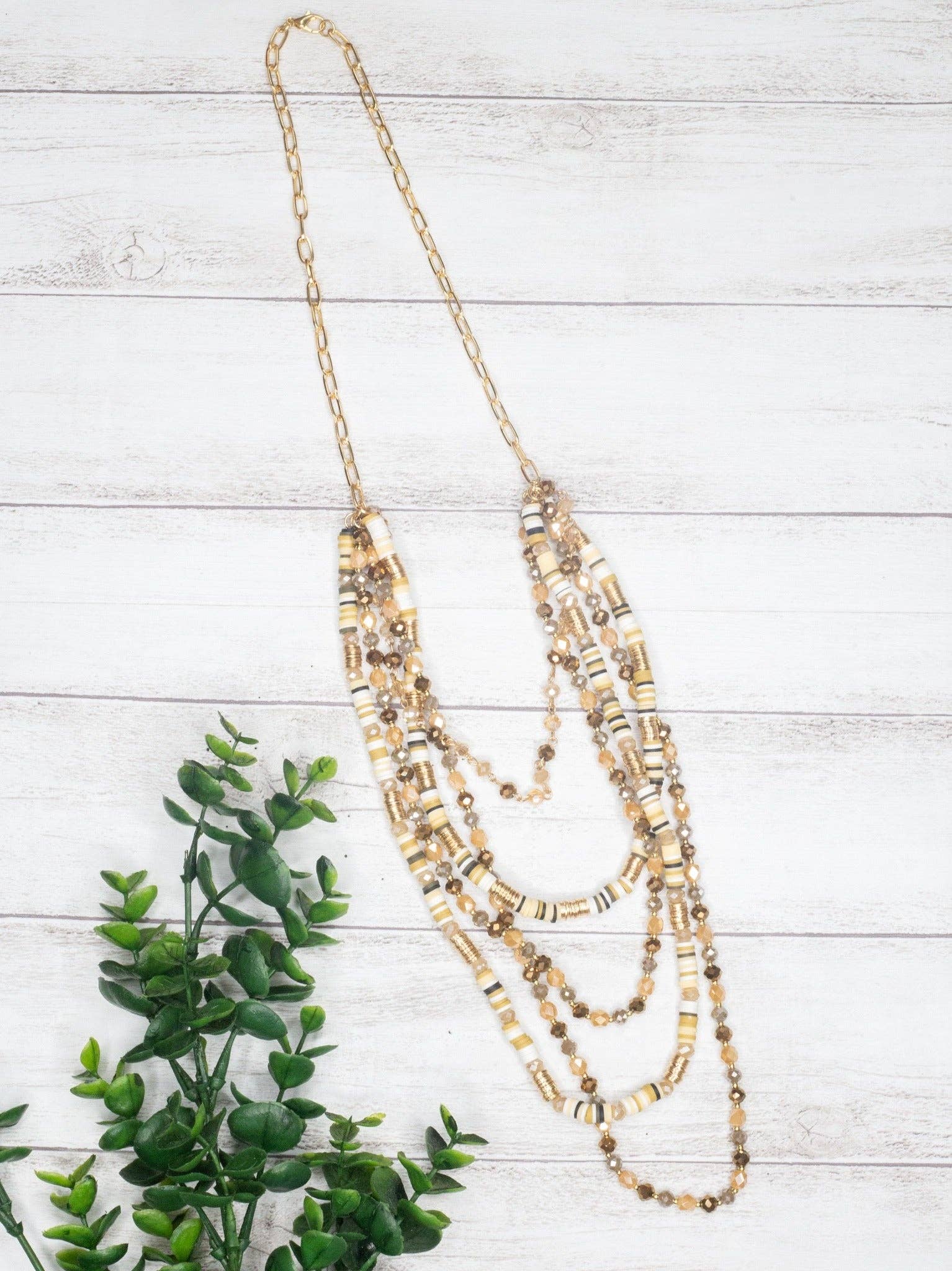 Tan Shell Beads With Mixed Crystal Beads Gold Link Chain Necklace - layred neceklace in shades of tans and ambers on a white wall