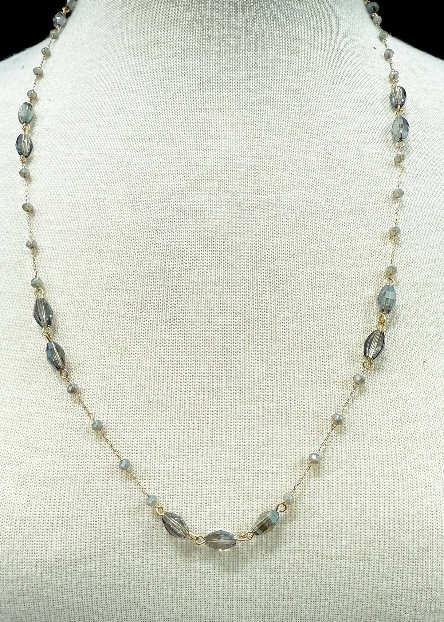 Necklace with gray & amber beads on a mannequin bust against a light background