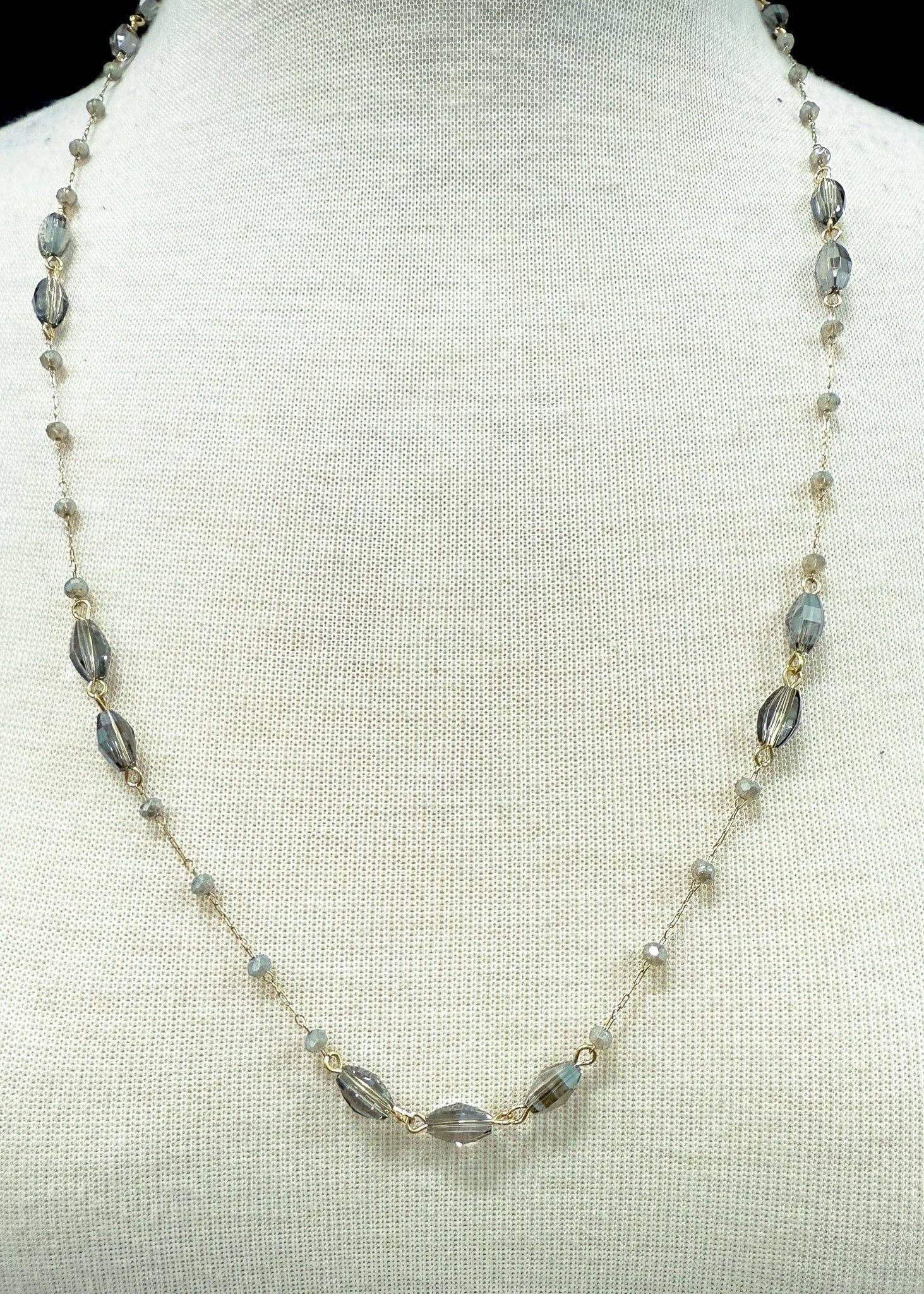 Necklace with gray & amber beads on a mannequin bust against a light background
