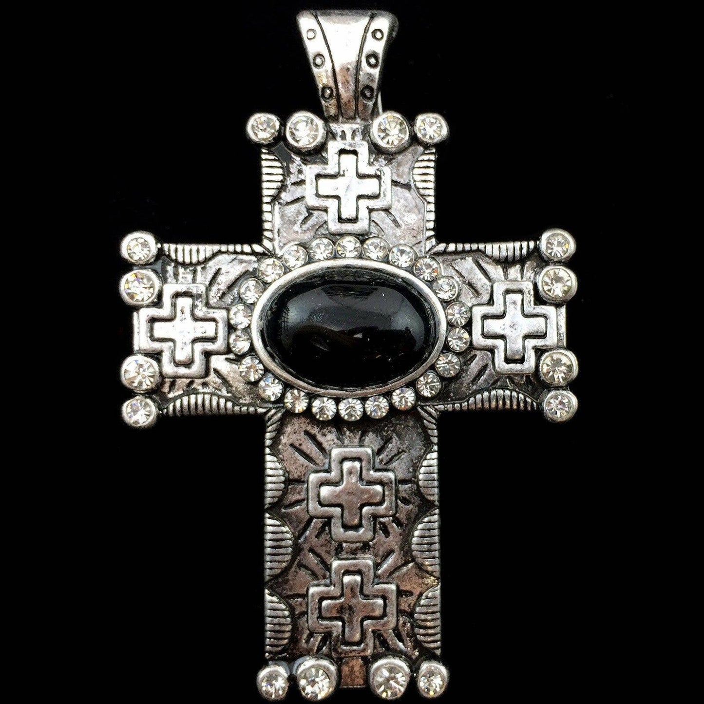 Decorative cross pendant with black stone and silver accents on a black background