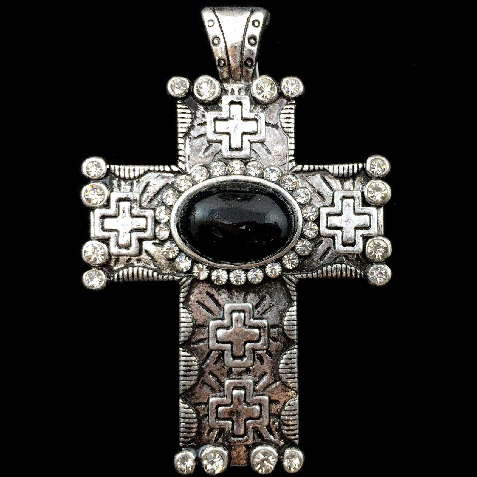 Decorative cross pendant with black stone and silver accents on a black background
