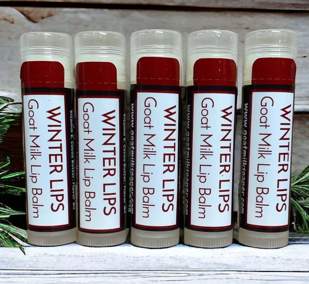 Six lip balms labeled 'Winter Lips Goat Milk Lip Balm' on a wooden surface.