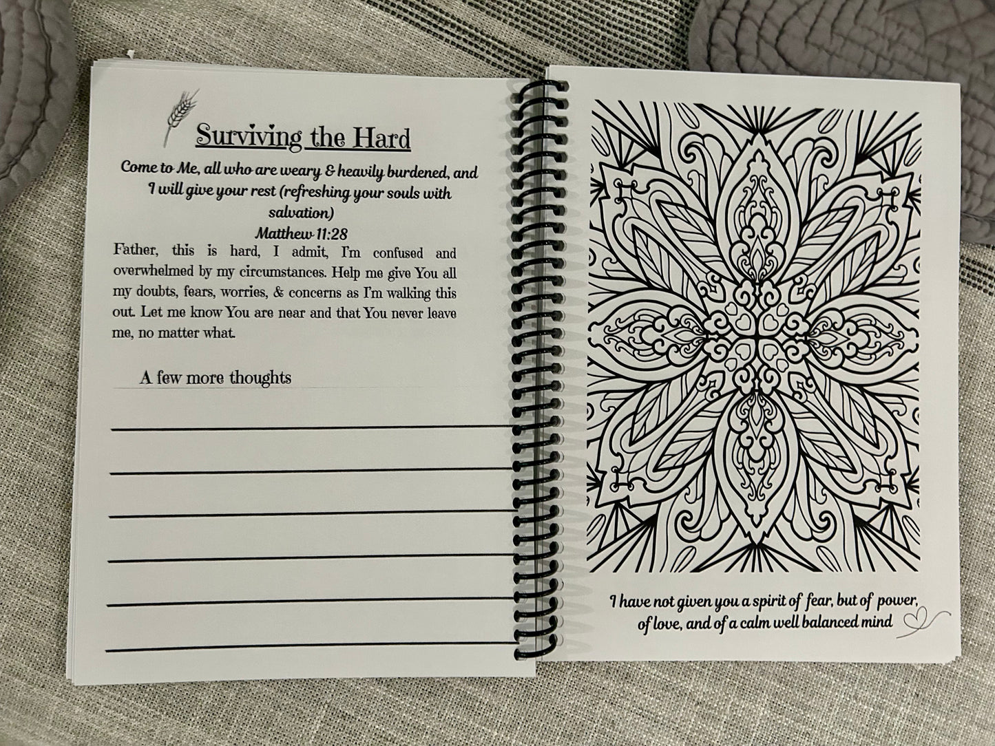 Open spiral-bound book with prayer and mandala coloring design on a textured surface