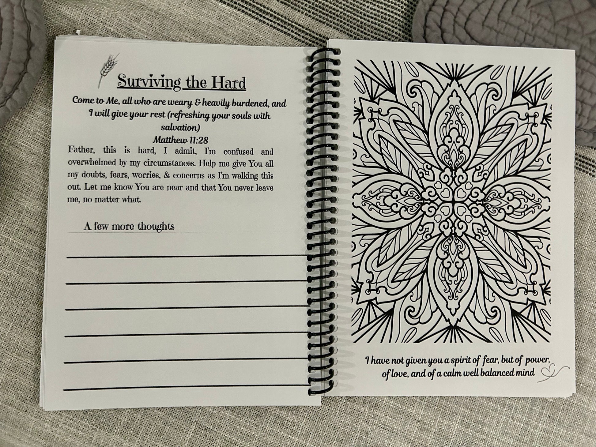 Open spiral-bound book with prayer and mandala coloring design on a textured surface