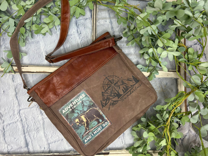 Immerse yourself in the thrill of the unknown with the Adventure Is Calling And I Must go. Zipper Closure Shoulder Bag, featuring a bear &amp; fish wilderness scene...compass and mountain range! Unique, Quality, + Character....

Measuring at 14" x 12.5" x 1.5", this bag is perfect for the woman on the go. It's not just a bag, but a statement piece that brings out your adventurous spirit. Crafted from repurposed tent and canvas, it embodies sustainability while maintaining a stylish appeal.

Inside zip pocke