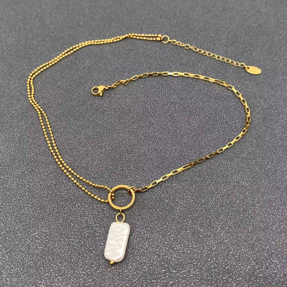 Gold chain necklace with a  pearl pendant on a gray background