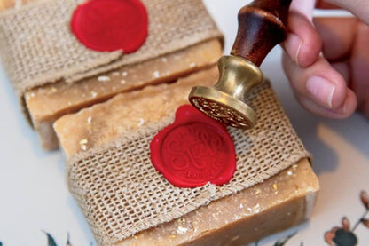 Three bars of soap with red wax seals on a textured surface