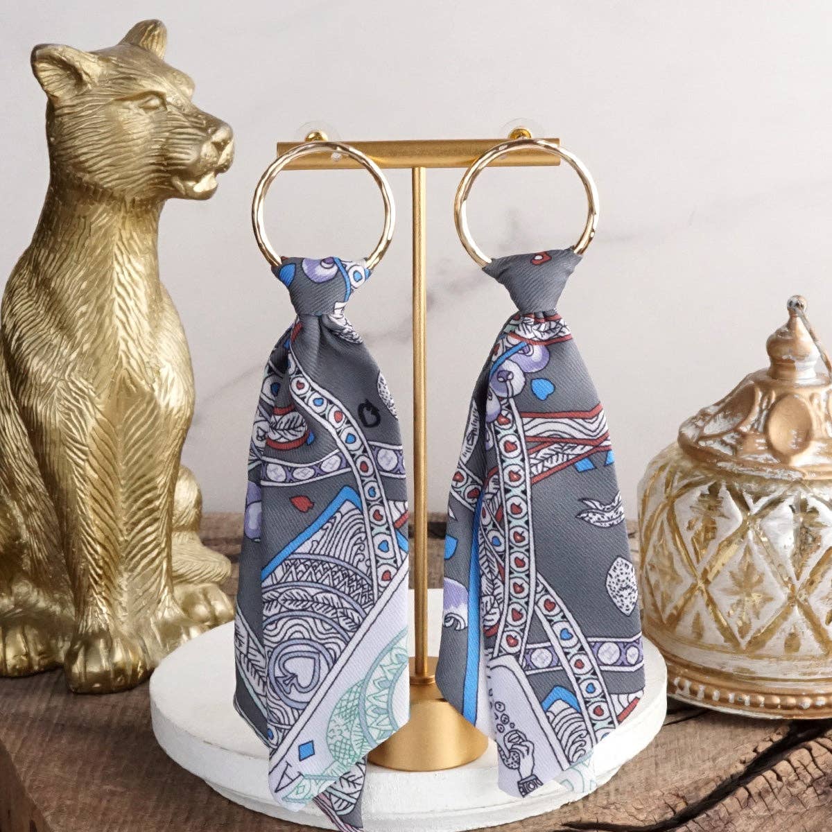 Decorative scarf holder with patterned scarves on a wooden surface with decorative items.