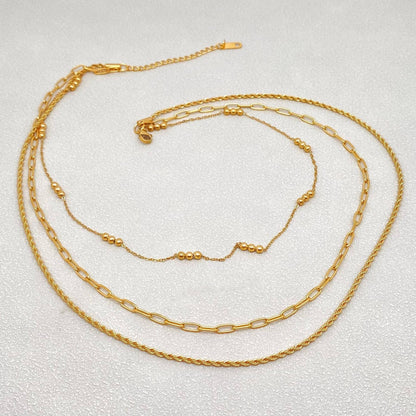 Three gold necklaces of different styles on a light gray background