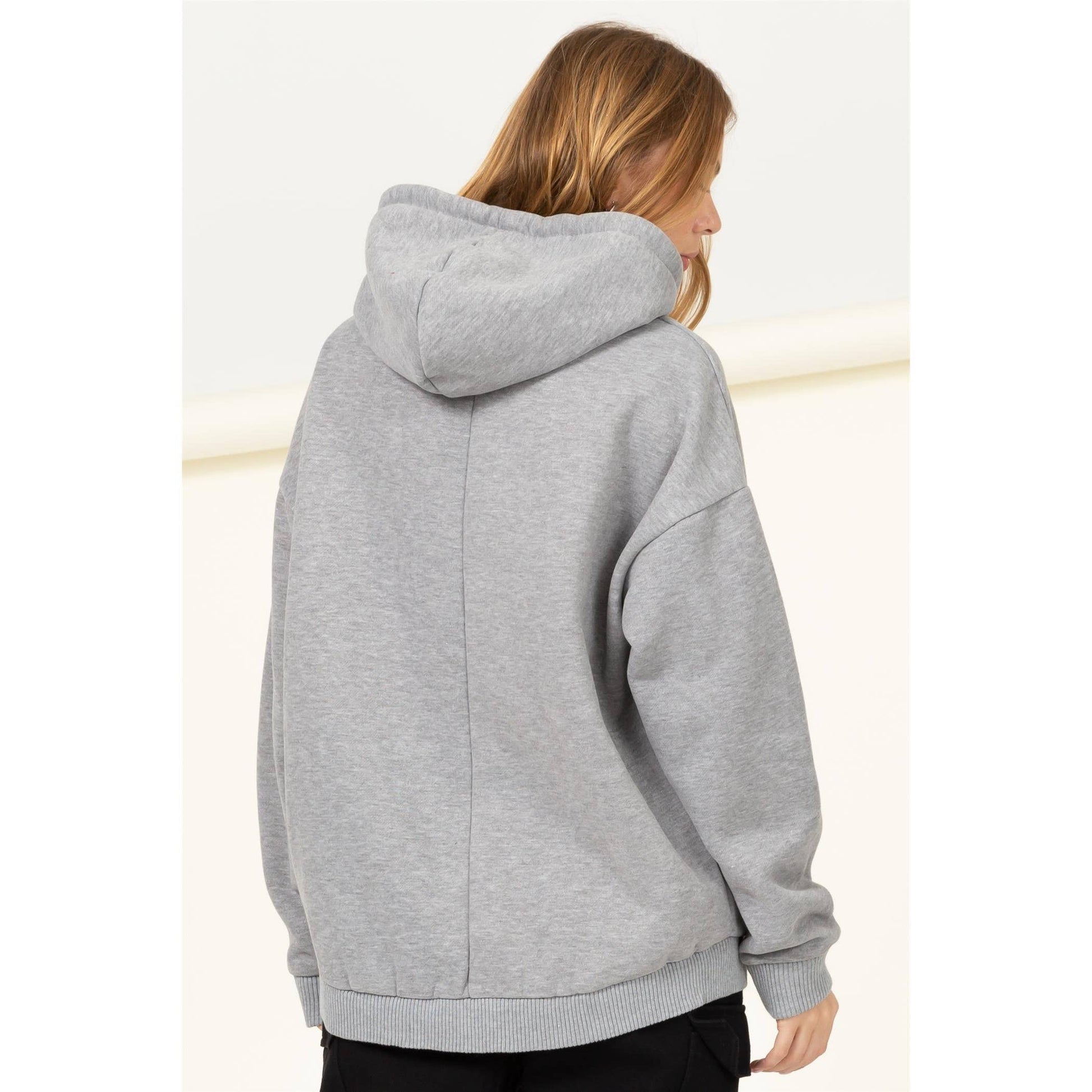 Person wearing a gray hoodie from behind on a light background