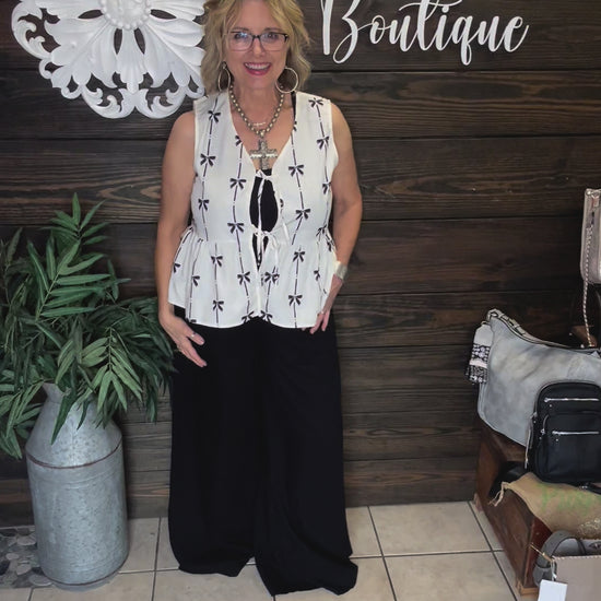 100% polyester cream colored vest with printed black bows, 2 ties in front to add to look, sleeveless. 